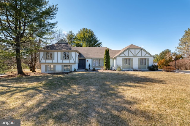 tudor house featuring a front yard and brick siding