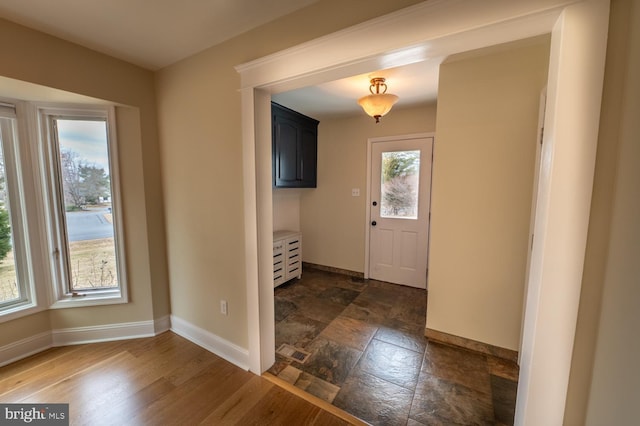 foyer with a wealth of natural light, stone finish flooring, and baseboards