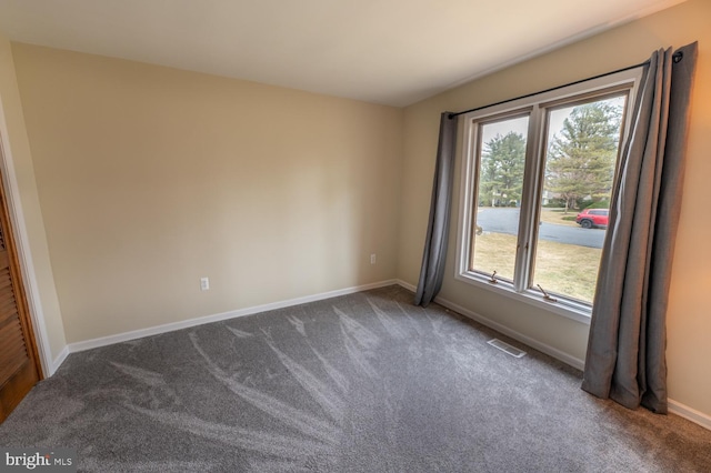 empty room featuring visible vents, baseboards, and dark colored carpet