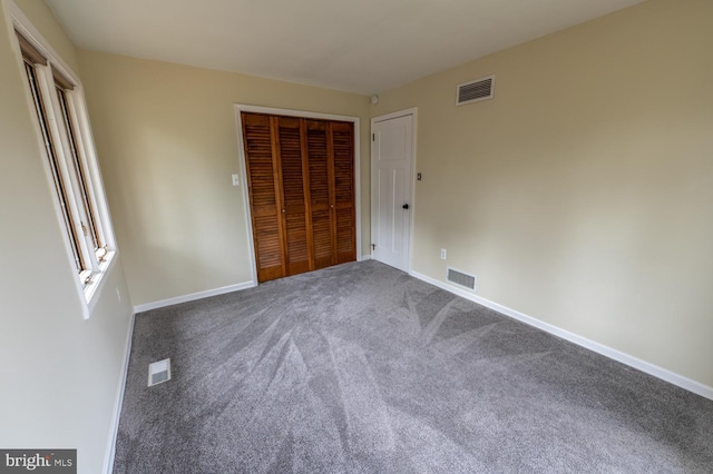 unfurnished bedroom featuring a closet, visible vents, and dark colored carpet