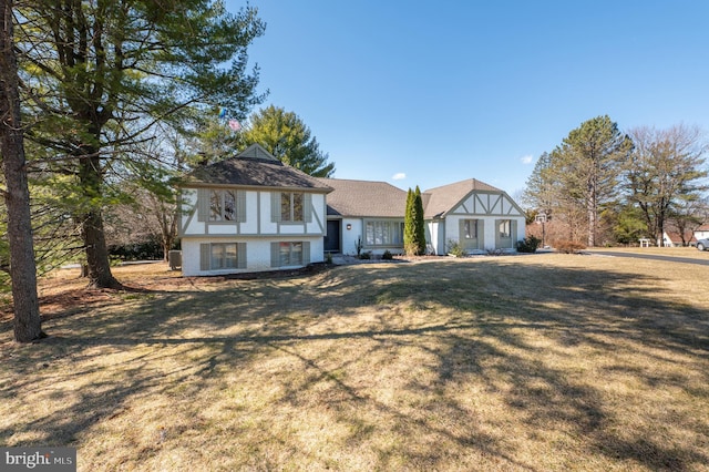 tudor home featuring brick siding and a front lawn