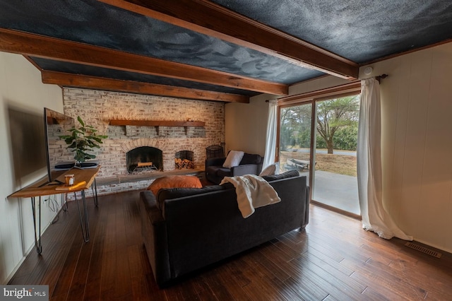 living area with visible vents, beam ceiling, hardwood / wood-style floors, and a fireplace