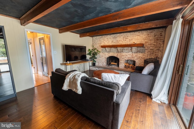 living area with dark wood-style floors, beamed ceiling, a fireplace, and brick wall