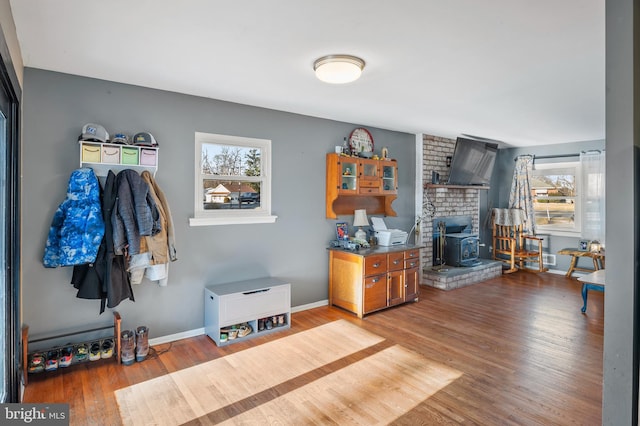 interior space with plenty of natural light, a wood stove, baseboards, and wood finished floors