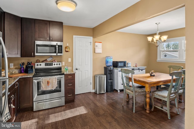 kitchen featuring dark wood-style floors, stainless steel appliances, dark brown cabinetry, light stone countertops, and a chandelier