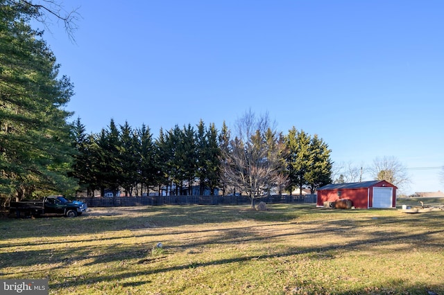 view of yard featuring an outbuilding, driveway, a garage, and fence