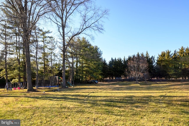 view of yard featuring playground community and a trampoline