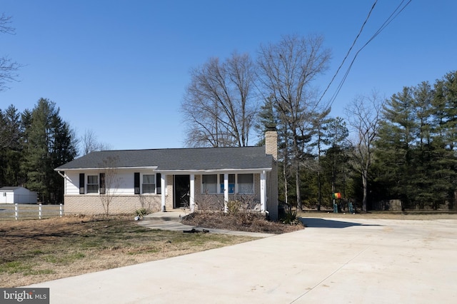 single story home featuring covered porch, brick siding, driveway, and a chimney