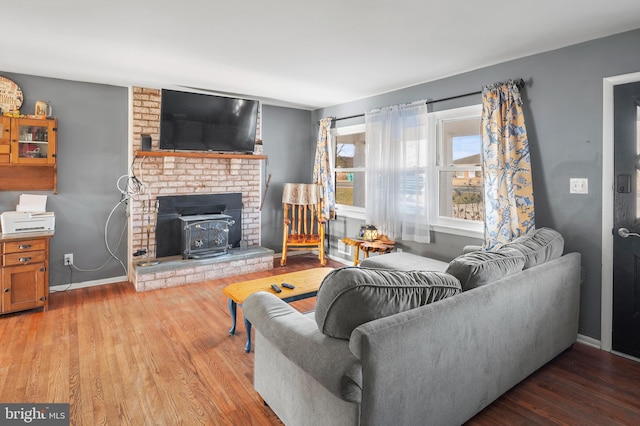 living area featuring baseboards, wood finished floors, and a wood stove