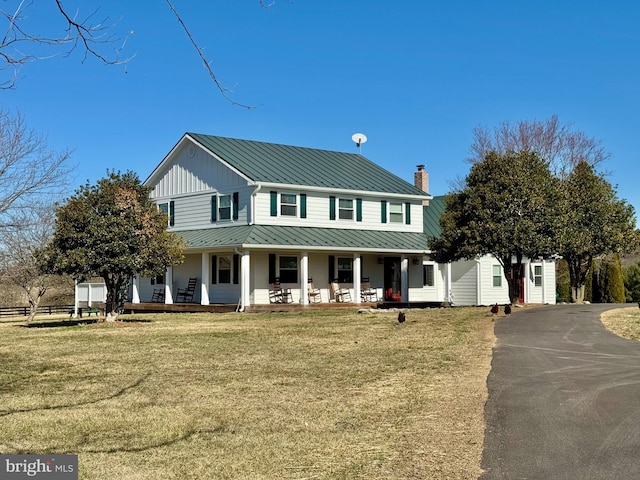 view of front of home with metal roof, covered porch, a front yard, and a standing seam roof