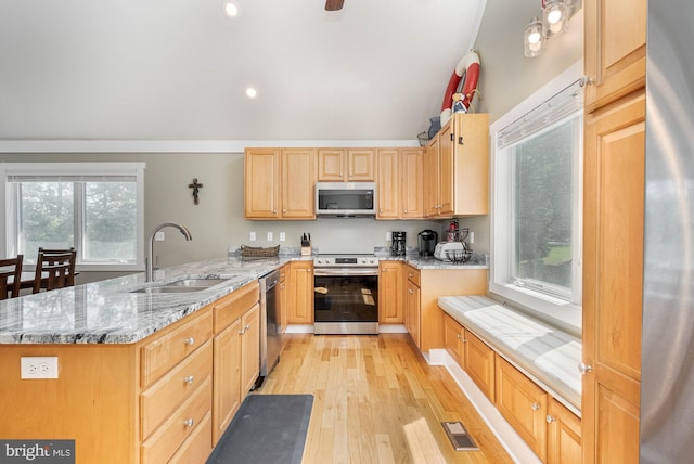 kitchen with a peninsula, a sink, visible vents, appliances with stainless steel finishes, and light stone countertops