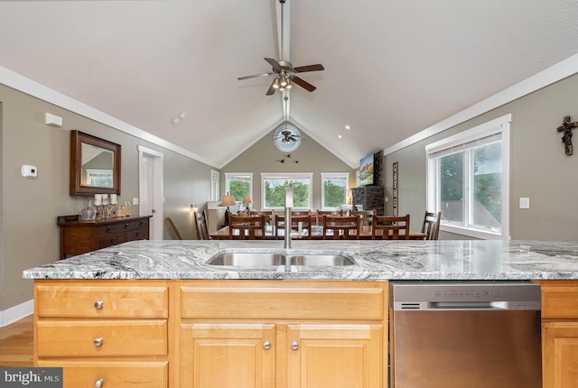 kitchen with lofted ceiling, light wood-style flooring, light stone countertops, stainless steel dishwasher, and a sink