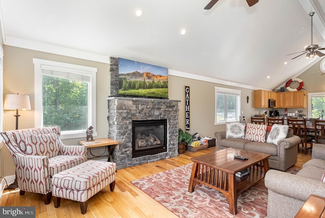 living area with lofted ceiling, recessed lighting, a fireplace, a ceiling fan, and light wood finished floors