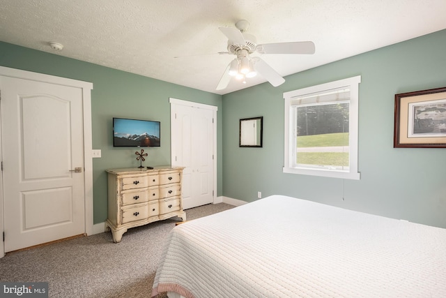 carpeted bedroom with a textured ceiling, a closet, a ceiling fan, and baseboards