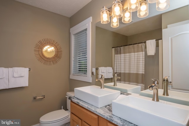 full bathroom with double vanity, a shower with shower curtain, a sink, and toilet