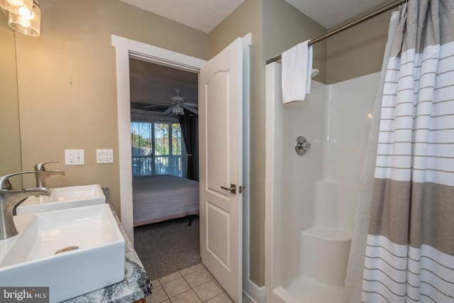 ensuite bathroom featuring connected bathroom, a shower with curtain, dual sinks, tile patterned flooring, and a textured ceiling