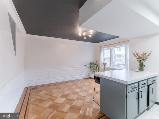 kitchen featuring wainscoting, a kitchen breakfast bar, light countertops, and crown molding