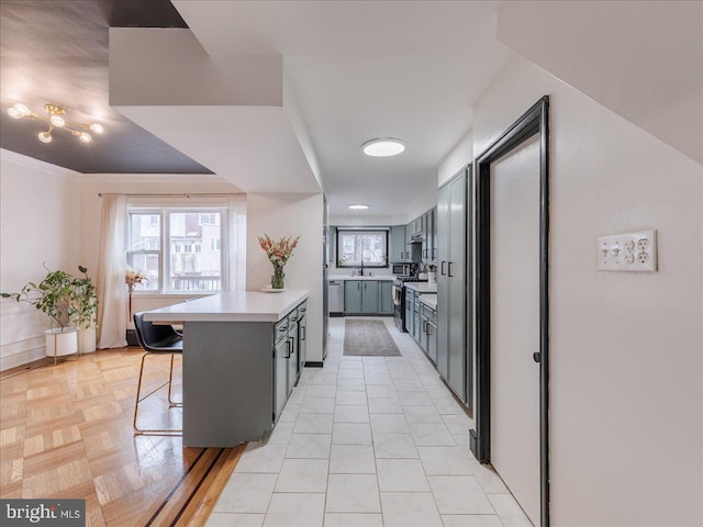 kitchen featuring a breakfast bar, a peninsula, a sink, light countertops, and appliances with stainless steel finishes