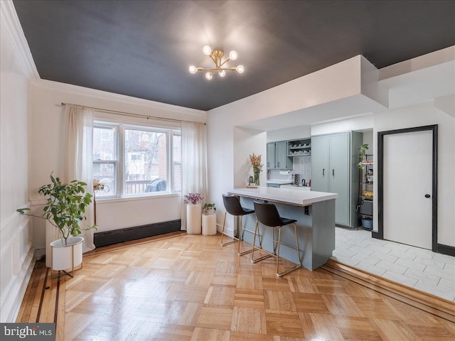 kitchen featuring an inviting chandelier, a peninsula, blue cabinetry, light countertops, and a kitchen breakfast bar