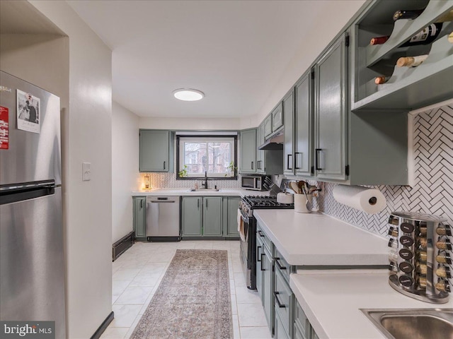 kitchen with backsplash, under cabinet range hood, light countertops, appliances with stainless steel finishes, and a sink