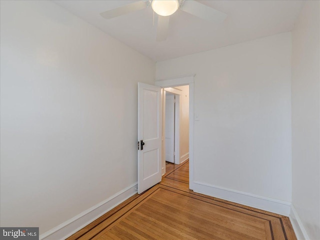 spare room featuring light wood-type flooring, baseboards, and a ceiling fan