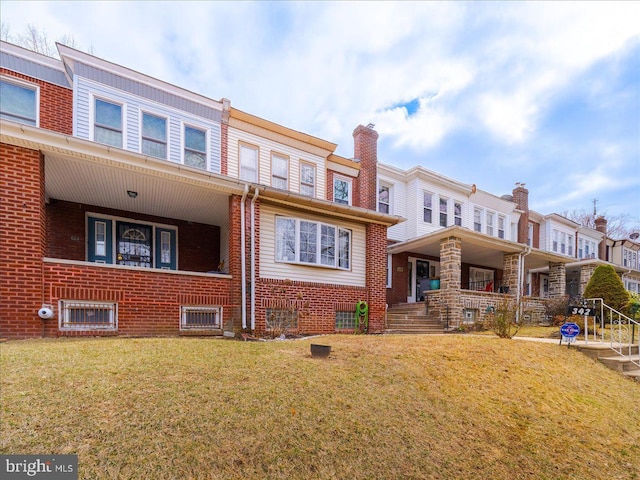 rear view of property with a yard, brick siding, and covered porch