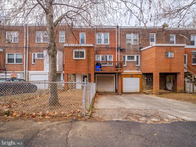 townhome / multi-family property featuring an attached garage, fence, brick siding, and driveway