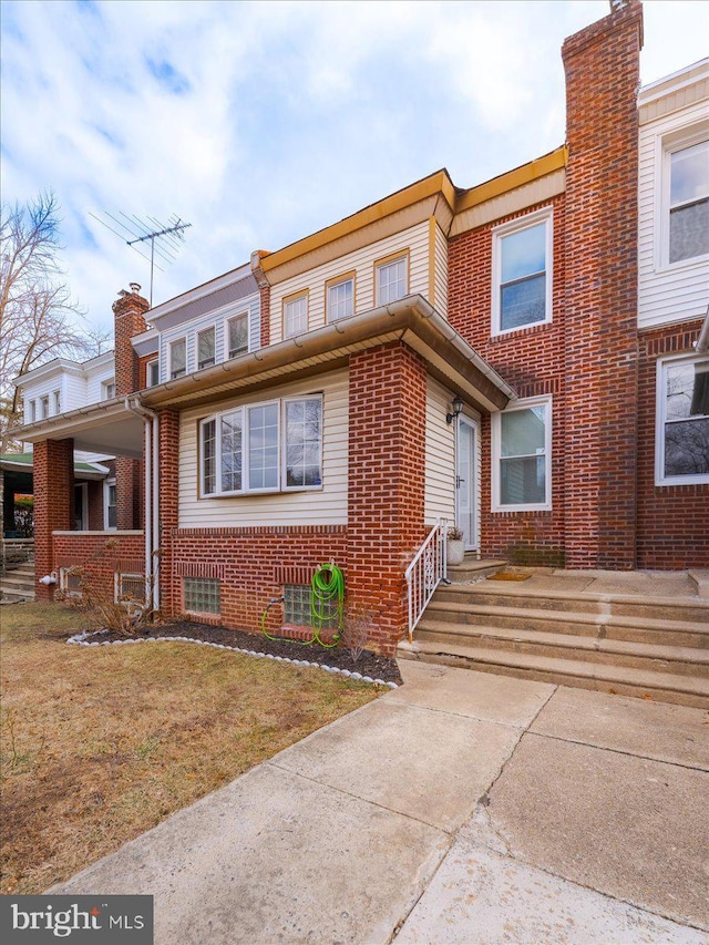 townhome / multi-family property with a front lawn, brick siding, and a chimney