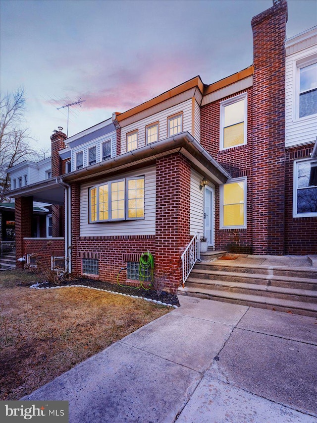 view of front of property featuring brick siding and a chimney