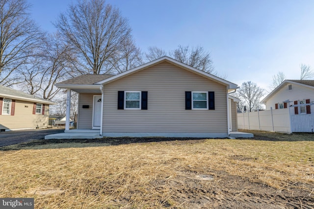 bungalow featuring a front lawn and fence