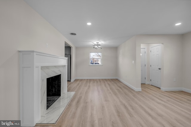 unfurnished living room featuring visible vents, baseboards, recessed lighting, a fireplace, and light wood-style floors