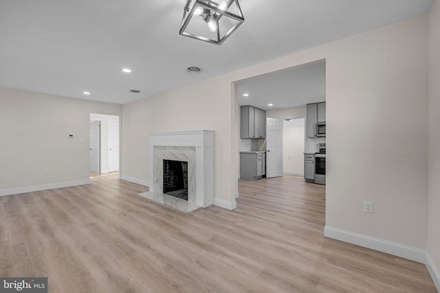 unfurnished living room featuring light wood-style flooring, recessed lighting, a fireplace, and baseboards