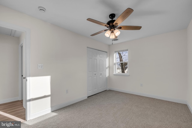 unfurnished bedroom with a closet, attic access, baseboards, and carpet floors