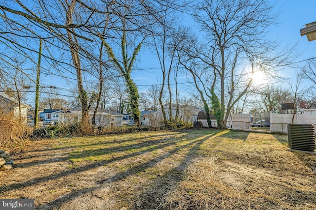 view of yard with central air condition unit, a trampoline, and fence