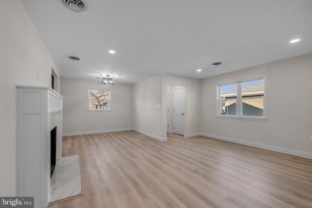 unfurnished living room featuring visible vents, a healthy amount of sunlight, a fireplace, and baseboards