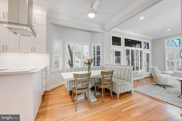 dining room featuring baseboards, ceiling fan, crown molding, and light wood finished floors