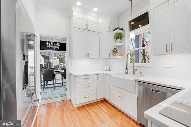 kitchen featuring a sink, stainless steel appliances, light countertops, white cabinets, and light wood-type flooring