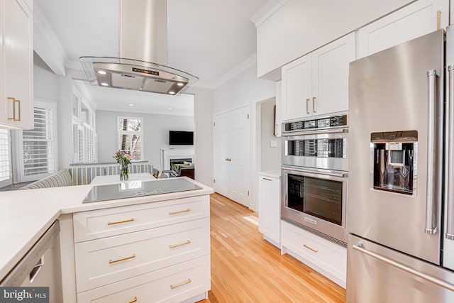 kitchen with crown molding, light countertops, island range hood, white cabinets, and stainless steel appliances