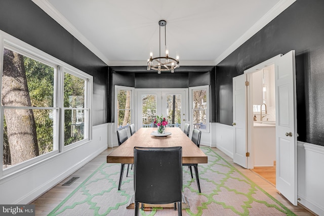 dining area featuring light wood-type flooring, visible vents, an inviting chandelier, and ornamental molding