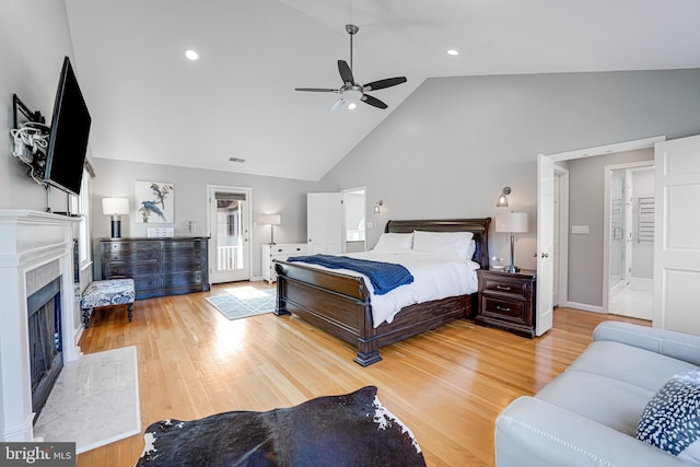 bedroom featuring baseboards, ceiling fan, a premium fireplace, wood finished floors, and high vaulted ceiling