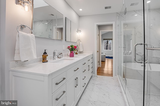 bathroom featuring visible vents, marble finish floor, a marble finish shower, a freestanding bath, and vanity