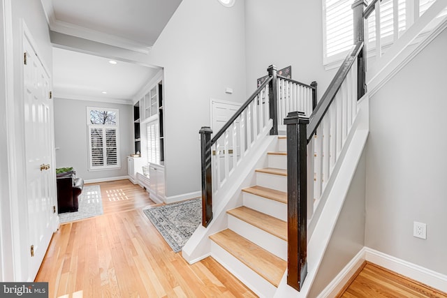 entryway with stairway, baseboards, wood finished floors, and ornamental molding