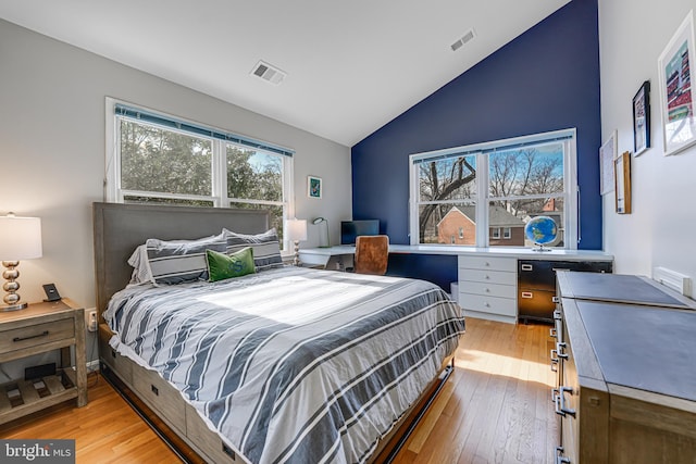 bedroom with visible vents, light wood-style flooring, and vaulted ceiling