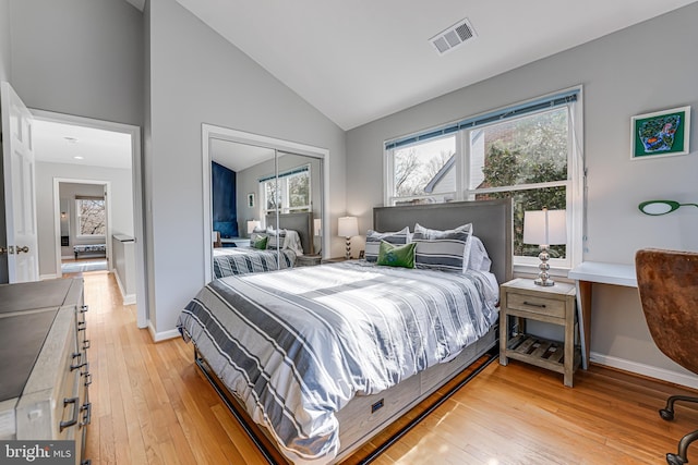 bedroom with baseboards, visible vents, light wood finished floors, high vaulted ceiling, and a closet