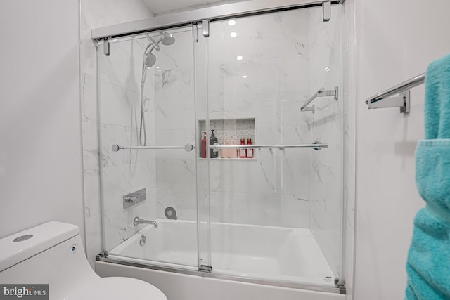 bathroom with toilet and bath / shower combo with glass door