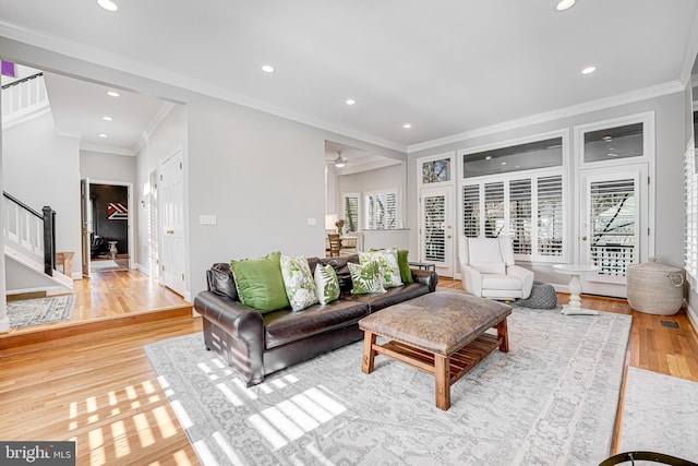 living room featuring baseboards, recessed lighting, ornamental molding, stairs, and light wood-style floors