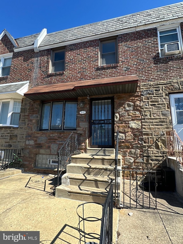 property entrance with mansard roof, a high end roof, and brick siding