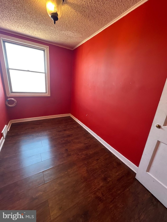 empty room featuring baseboards, wood finished floors, visible vents, and a textured ceiling