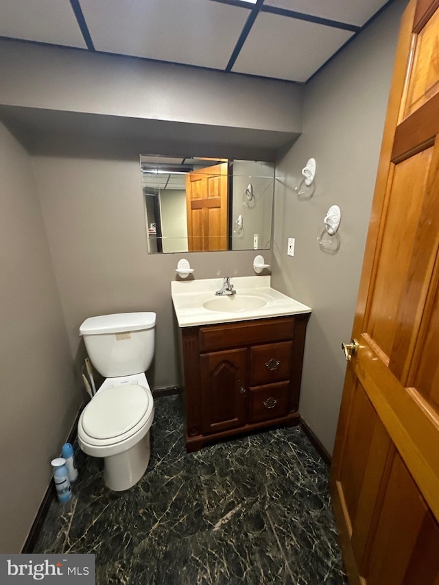 half bath featuring vanity, toilet, baseboards, and marble finish floor