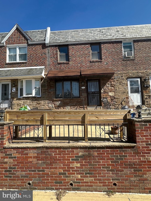 back of property featuring brick siding, a high end roof, mansard roof, and a fenced front yard